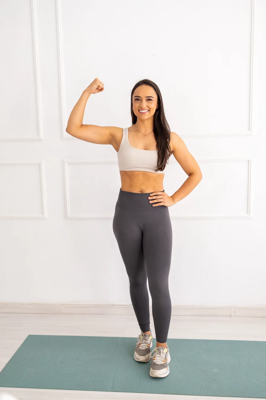 Bianca Cardoso em pé, sorrindo e flexionando o braço